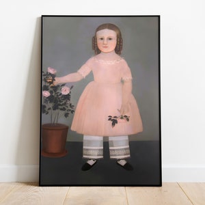Op de afbeelding: Ingelijst portret van een jong meisje in een roze jurk en een witte broek met een bloemenmotief. Ze houdt rozen vast en staat naast een rozenstruik in pot. Het kunstwerk heeft een vintage esthetiek.