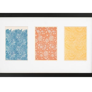 Pu&ograve; includere: Una cornice nera con tre stampe a motivi diversi all'interno. Le stampe sono in tonalit&agrave; di blu, arancione e giallo.