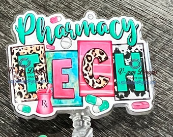 May include: A teal, pink, and black Pharmacy Tech badge reel with a leopard print design. The badge reel has a green heart charm and a sparkly silver charm. The text "V-spin Designs" and "CREATIVE CRAFTS" is printed on the bottom of the badge reel.