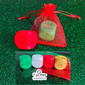 May include: A collection of colorful dice with holiday movie titles, including "Elf," "Christmas Story," and "Home Alone." The dice are red, green, white, and yellow, with text in a sans-serif font. A red mesh bag is also included.