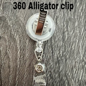 Peut inclure: Un clip alligator transparent en plastique &agrave; 360 degr&eacute;s avec un clip en m&eacute;tal argent&eacute;. Le clip est attach&eacute; &agrave; un cordon r&eacute;tractable en plastique transparent.