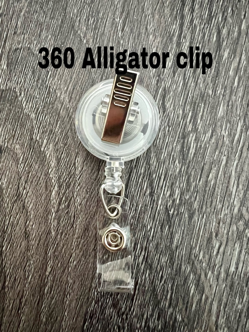 Peut inclure: Un clip alligator transparent en plastique &agrave; 360 degr&eacute;s avec un clip en m&eacute;tal argent&eacute;. Le clip est attach&eacute; &agrave; un cordon r&eacute;tractable en plastique transparent.