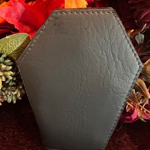 May include: A black leather coffin-shaped box with a stitched edge.