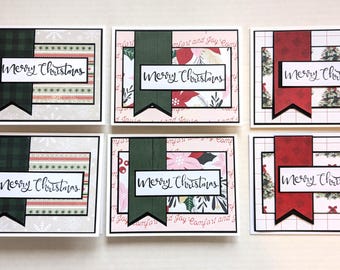 May include: Six rectangular greeting cards featuring the text Merry Christmas. Two cards have a grey snowflake background with a green plaid banner. Two cards feature poinsettias and green banners. Two cards show Christmas trees with red banners.