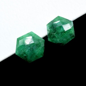 Puede incluir: Dos cuentas de piedra preciosa facetadas de color verde. Las cuentas son hexagonales y tienen un acabado pulido.