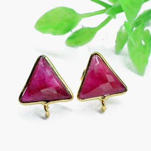 May include: A pair of gold-toned earrings with triangular red gemstone accents.