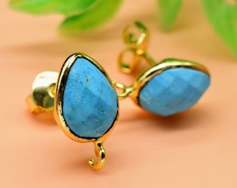 May include: A pair of gold earrings with blue teardrop-shaped stones. The stones have a faceted texture.