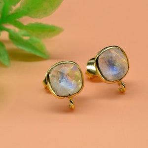 May include: A pair of gold earrings with a square-shaped moonstone gemstone. The earrings have a small gold hook on the bottom.