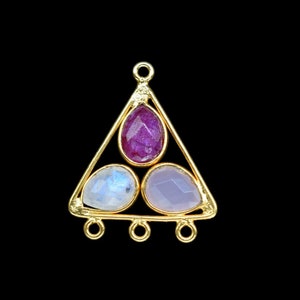 Puede incluir: Colgante de triángulo de oro con tres gotas de piedras preciosas. La piedra superior es de color rosa intenso, la piedra de la izquierda es una piedra de luna blanca y la piedra de la derecha es de color púrpura claro.