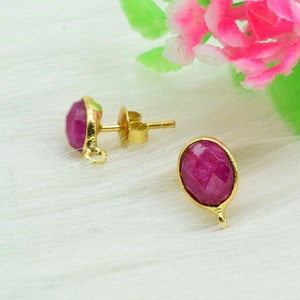 May include: A pair of gold earrings with pink gemstone accents. The earrings have a simple design and are perfect for everyday wear.