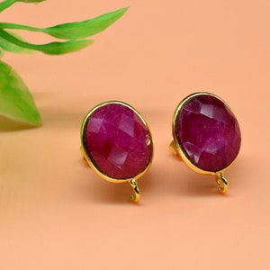 Pode incluir: Um par de brincos de ouro com detalhes de pedras preciosas cor-de-rosa. Os brincos têm um design simples e são perfeitos para o uso diário.