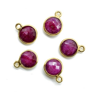 Può includere: Cinque ciondoli dorati con pietre rotonde di rubino rosso sfaccettate. Ogni ciondolo ha un piccolo anello per attaccarlo a gioielli.