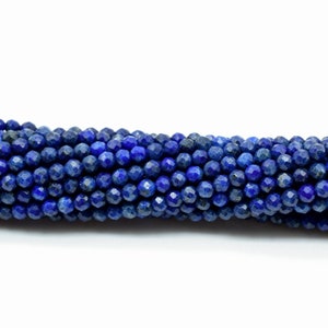 May include: A strand of deep blue lapis lazuli beads, each bead is faceted and has a slightly irregular shape. The beads are strung together to create a long necklace or bracelet.