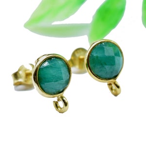 May include: A pair of gold earrings with green gemstone accents. The earrings have a simple design with a round gemstone and a small loop.