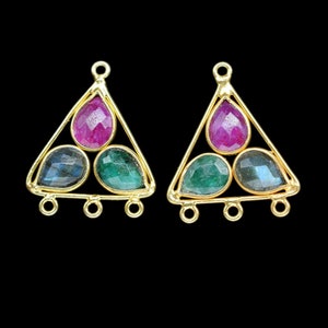 May include: A pair of gold triangle-shaped earring findings with three gemstone accents. The gemstones are a pink ruby, a green emerald, and a blue labradorite.