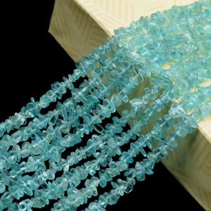 Può includere: Un filo di perline di aquamarina blu chiaro a forma di chip. Le perline sono di forma irregolare e hanno un aspetto traslucido.