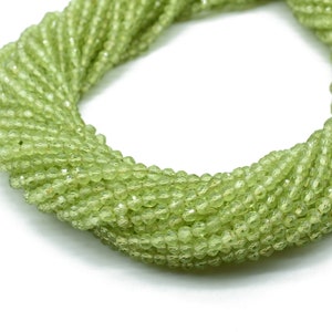 May include: A strand of light green peridot beads, faceted and round, strung together in a long necklace.