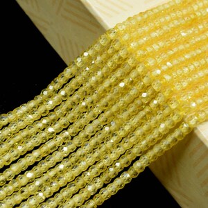 Può includere: Un filo di perline di vetro giallo sfaccettate. Le perline sono piccole e rotonde, e hanno una finitura lucida e iridescente.