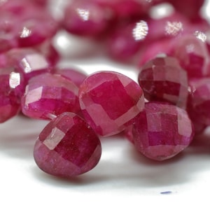 Może przedstawiać: Szereg fasetowanych koralików rubinowych w intensywnym czerwonym kolorze. Koraliki mają kształt serca i polerowane wykończenie.