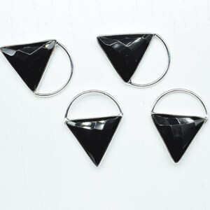 May include: Four black triangle shaped gemstone pendants with silver hoops. The pendants are on a white surface.