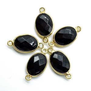 May include: Five black oval gemstone connectors with gold-toned metal settings. Each connector has two loops for attaching to jewelry.