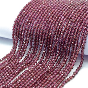 May include: A strand of deep red faceted garnet beads. The beads are small and round, and they have a shiny, polished finish.