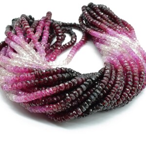 May include: A strand of faceted gemstone beads in a gradient of pink, red, and black. The beads are small and round, and they are strung on a clear thread.