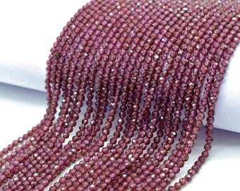 May include: A strand of deep red faceted garnet beads. The beads are small and round, and they have a shiny, polished finish.
