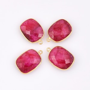 May include: Four gold-plated pendant charms with a red gemstone in a rectangular shape. Each charm has a loop for attaching to a necklace or bracelet.