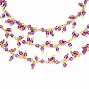 以下が含まれることがあります： 繊細なゴールドチェーンと小さなパープルビーズがついたマルチストランドネックレス。ビーズはカスケード状に配置されており、繊細でフェミニンなルックを生み出しています。