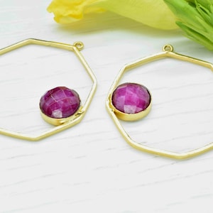 May include: A pair of gold-toned octagonal hoop earrings with a pink gemstone in each hoop.