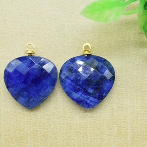 Peut inclure: Deux pendentifs en forme de cœur en pierre bleue avec des anneaux de saut en or. Les pierres précieuses sont facettées et ont une couleur bleu foncé.