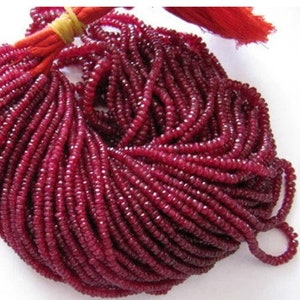 May include: A strand of deep red ruby beads, each bead is faceted and has a slightly rounded shape. The beads are strung on a thin cord and are ready to be used for jewellery making.