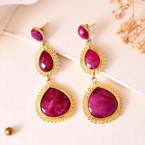 Puede incluir: Un par de pendientes de oro con tres piedras de color rosa en forma de lágrima. Las piedras están engastadas en filigrana de oro.