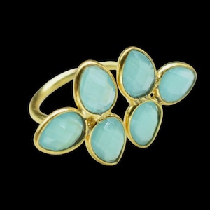 Pode incluir: Anel de ouro com cinco detalhes de pedras preciosas azuis claras em forma de flor.