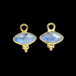 May include: A pair of gold-tone earrings with a blue moonstone eye charm. Each charm has three small gold beads hanging from the bottom.