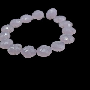 May include: A strand of pale lavender gemstone beads, each bead is faceted and shaped like a flower.