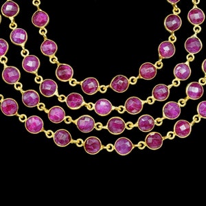 May include: A multi-strand necklace featuring round, faceted ruby-coloured stones set in gold.