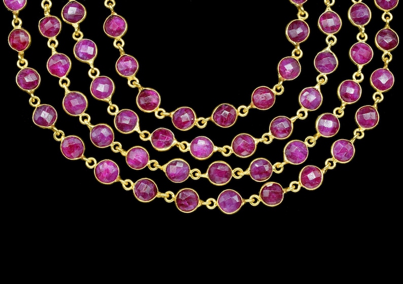 May include: A multi-strand necklace featuring round, faceted ruby-coloured stones set in gold.