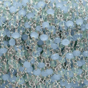 May include: A silver chain with light blue faceted beads. The chain is made of small, delicate links and the beads are evenly spaced.