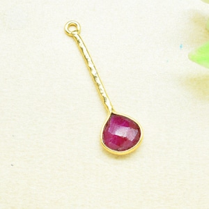 Pode incluir: Um pingente de ouro com uma gema de rubi em forma de lágrima. O pingente tem uma corrente de ouro martelada.