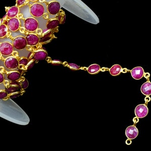 May include: A spool of gold chain with pink gemstone beads. The chain is made of small, round links and the beads are faceted and have a shiny finish.