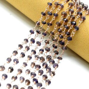 May include: A strand of dark purple gemstone beads strung on a rose gold chain. The beads are faceted and have a slightly irregular shape.