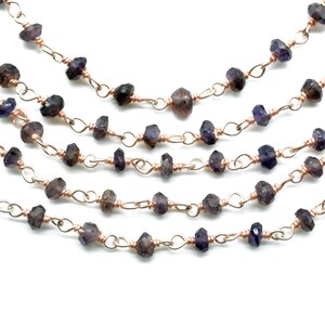 May include: A strand of dark purple gemstone beads strung on a copper wire chain. The beads are faceted and have a slightly irregular shape. The chain is made of small, linked loops.