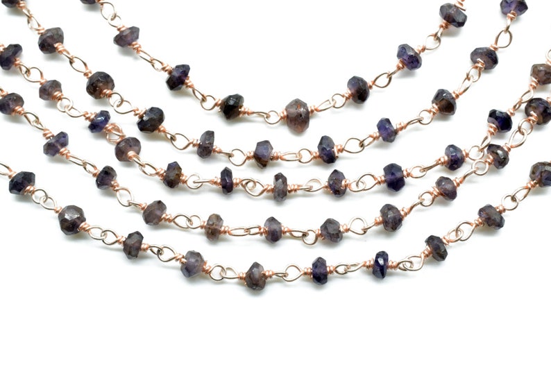 May include: A strand of dark purple gemstone beads strung on a copper wire chain. The beads are faceted and have a slightly irregular shape. The chain is made of small, linked loops.