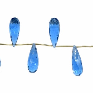 May include: A strand of six teardrop-shaped blue topaz beads strung on a gold wire.