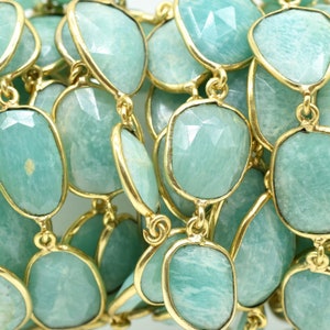 May include: A strand of light green gemstone beads with gold accents. The beads are oval shaped and have a faceted finish.