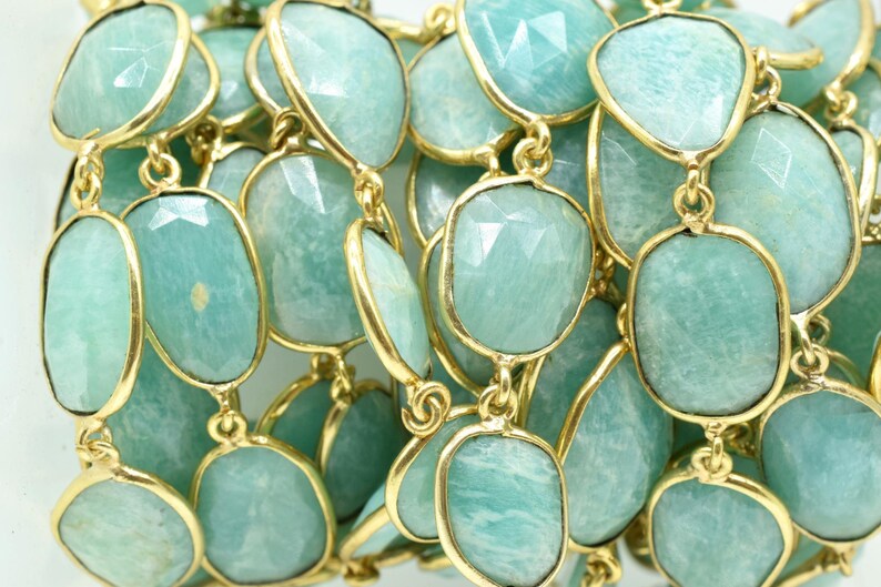 May include: A strand of light green gemstone beads with gold accents. The beads are oval shaped and have a faceted finish.