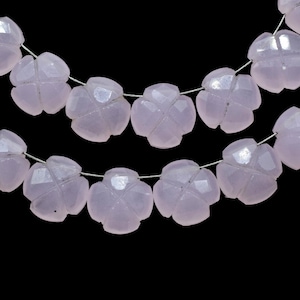 May include: A strand of pale pink gemstone beads, each bead is carved in the shape of a four-leaf clover. The beads are strung on a silver wire.
