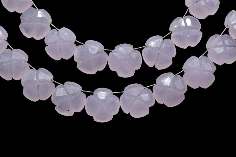 May include: A strand of pale pink gemstone beads, each bead is carved in the shape of a four-leaf clover. The beads are strung on a silver wire.